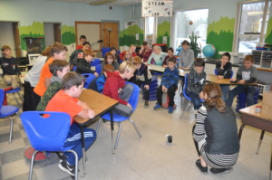 Fourth graders in Charlie Cummings Fisher Elementary School Class watch a Cubelets robot created by Mack Molding Engineering Team Leader Ann Weddell drive across the floor.