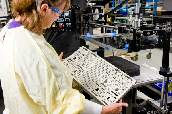 Photo of contact manufacturing services manufacturing line. Staff member finishing a part.